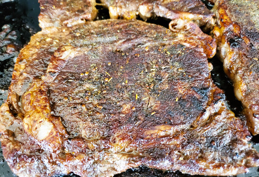 Image of steak cooking on a griddle.