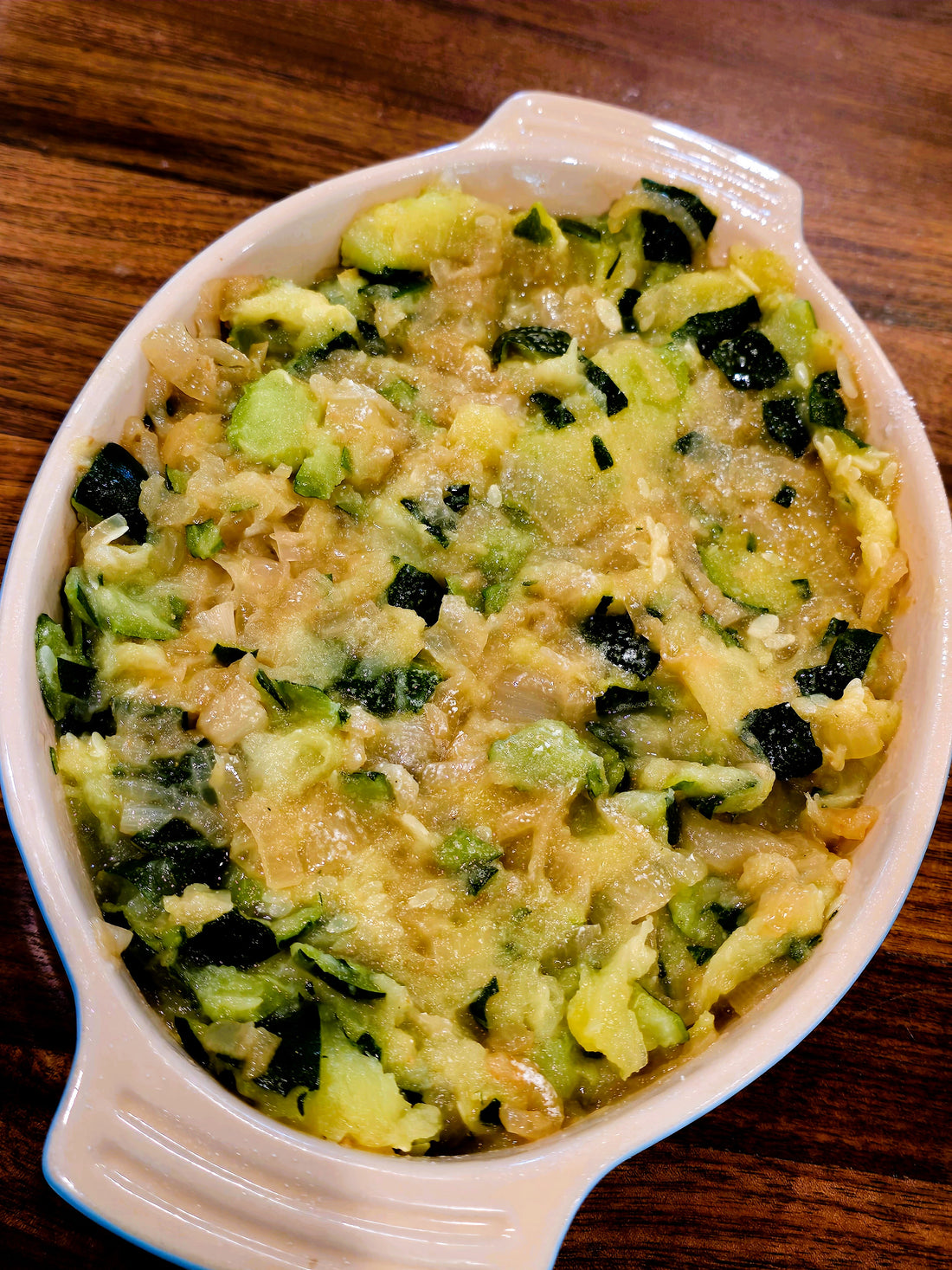 Image of green zucchini casserole with white cheese on top.